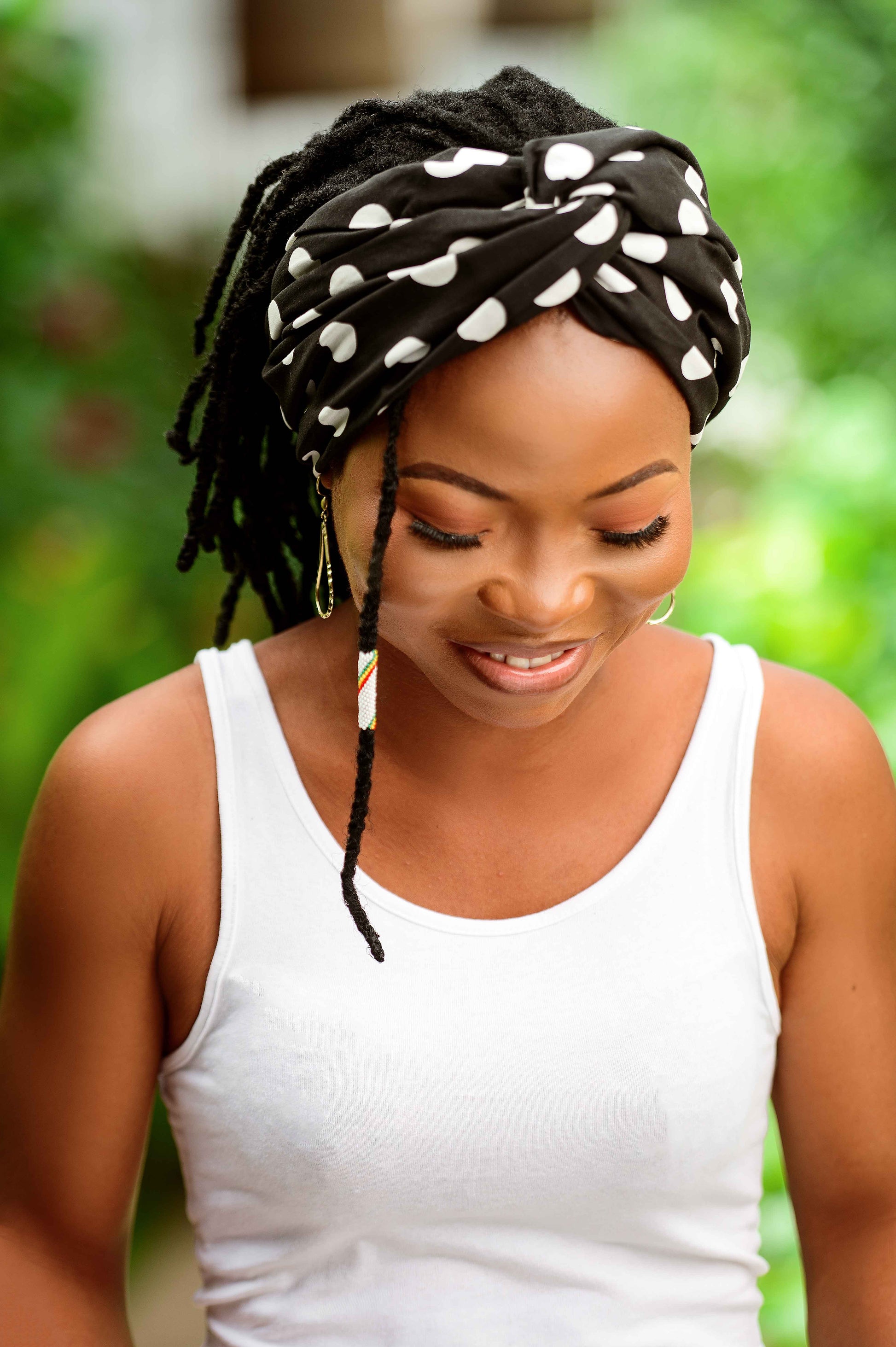 Découvrez le foulard pré-noué 2-en-1 PEAS, présenté de face. Fabriqué à la main au Togo en 100 % coton, ce foulard modulable et flexible se porte en bandeau ou en turban. Avec ses motifs uniques, il apporte une touche rétro chic à vos tenues.